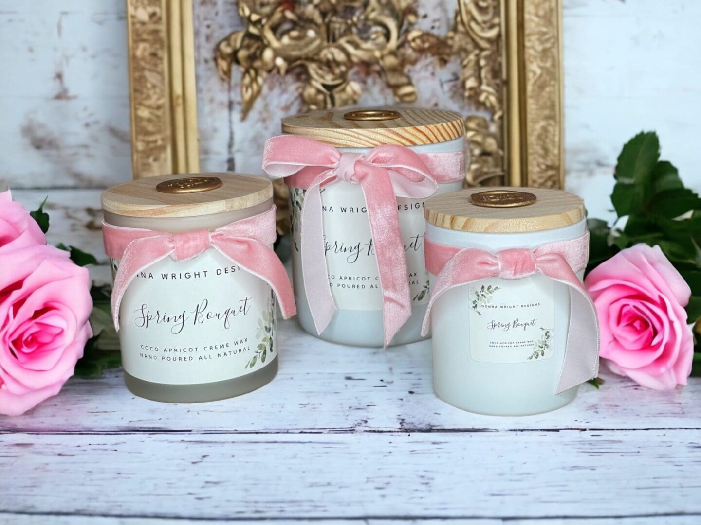 Donna Wright Designs Three elegant "Spring Bouquet Candles" with pale pink ribbons and rose decorations, labeled "Spring Bouquet Candles," set against a rustic wooden background with golden ornate frames.