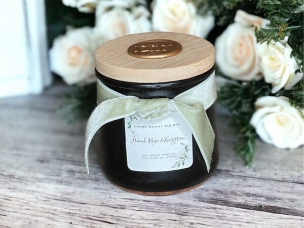 Scented candles with wooden wicks by Donna Wright Designs in French Rose & Evergreen limited edition 4 oz candle sitting on an antique wooden table. The best romantic fragrance combination!
