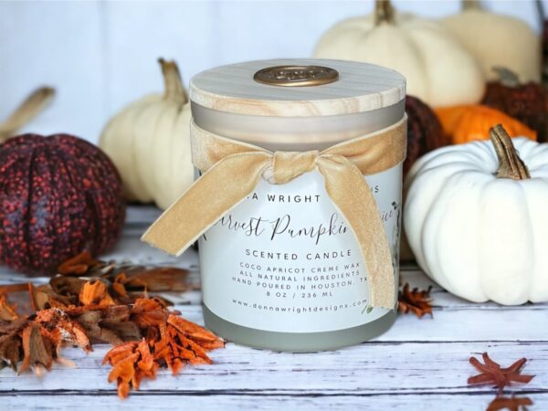 A candle with pumpkins and leaves on it.