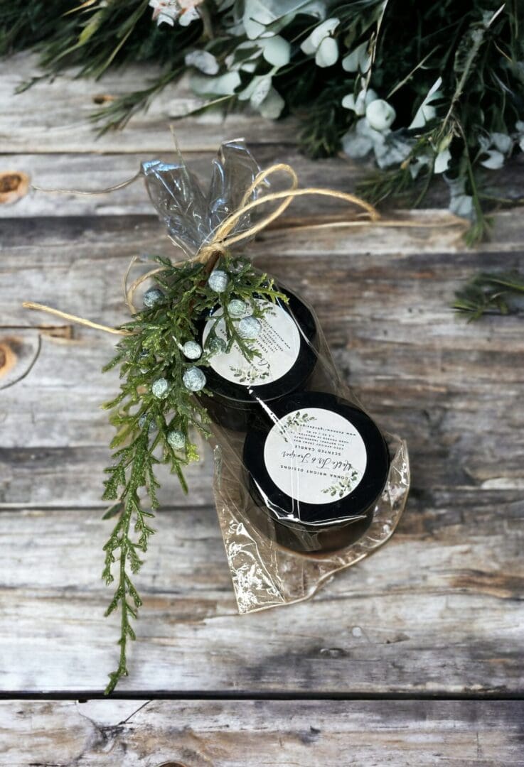 Two small jars of Noble Fir & Juniper - 4 Oz sitting on a wooden table.