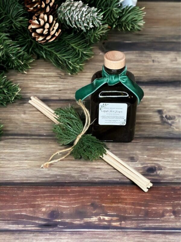 Noble Fir & Juniper reed diffuser by Donna Wright Designs is the best pine scented reed diffuser housed in an olive-colored glass jar with cork and seven reeds.