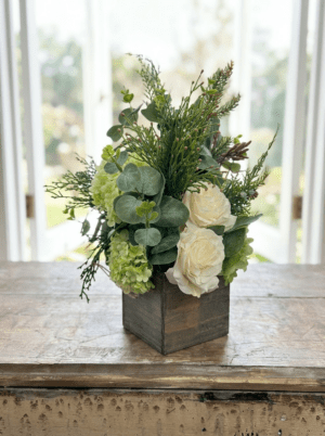 The Small Floral in Wood Box features white roses, green hydrangeas, eucalyptus leaves, and assorted greenery for a charming rustic display.