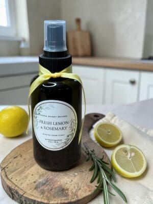 Luxury lemon rosemary room spray with citrus and herbs on marble and linen background.